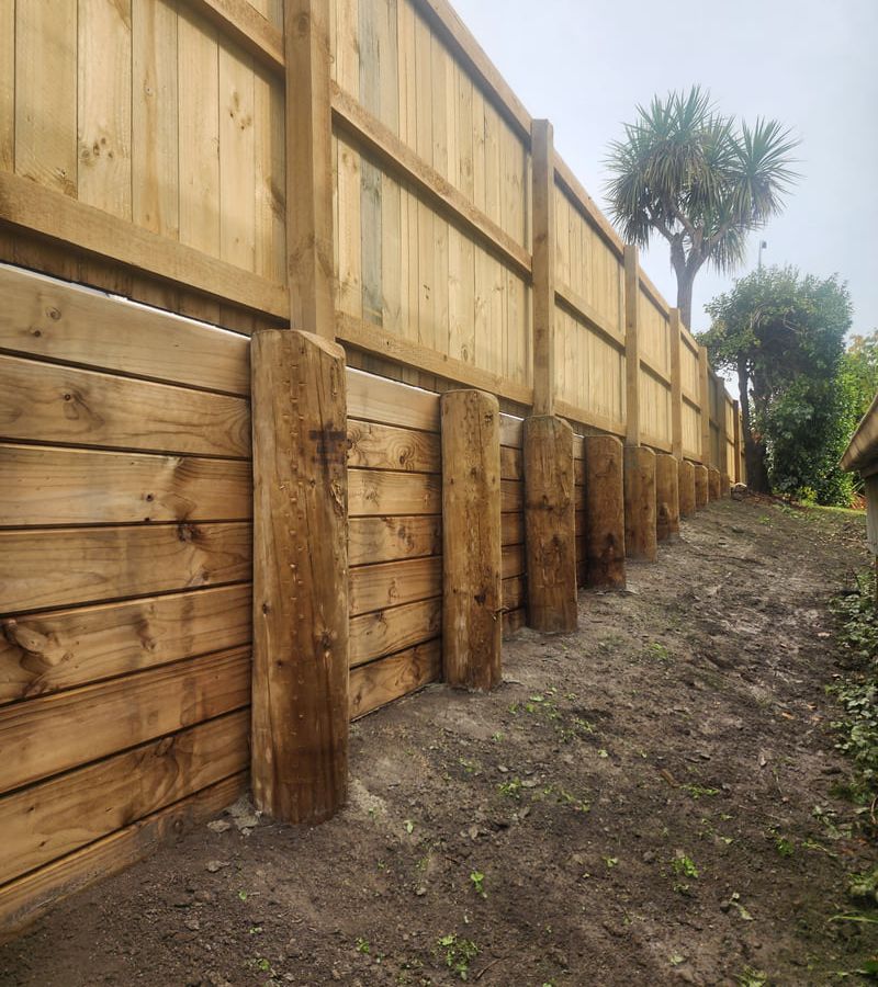 Professional retaining wall construction showing quality timber wall and proper drainage installation for slope stabilization in Nelson Tasman